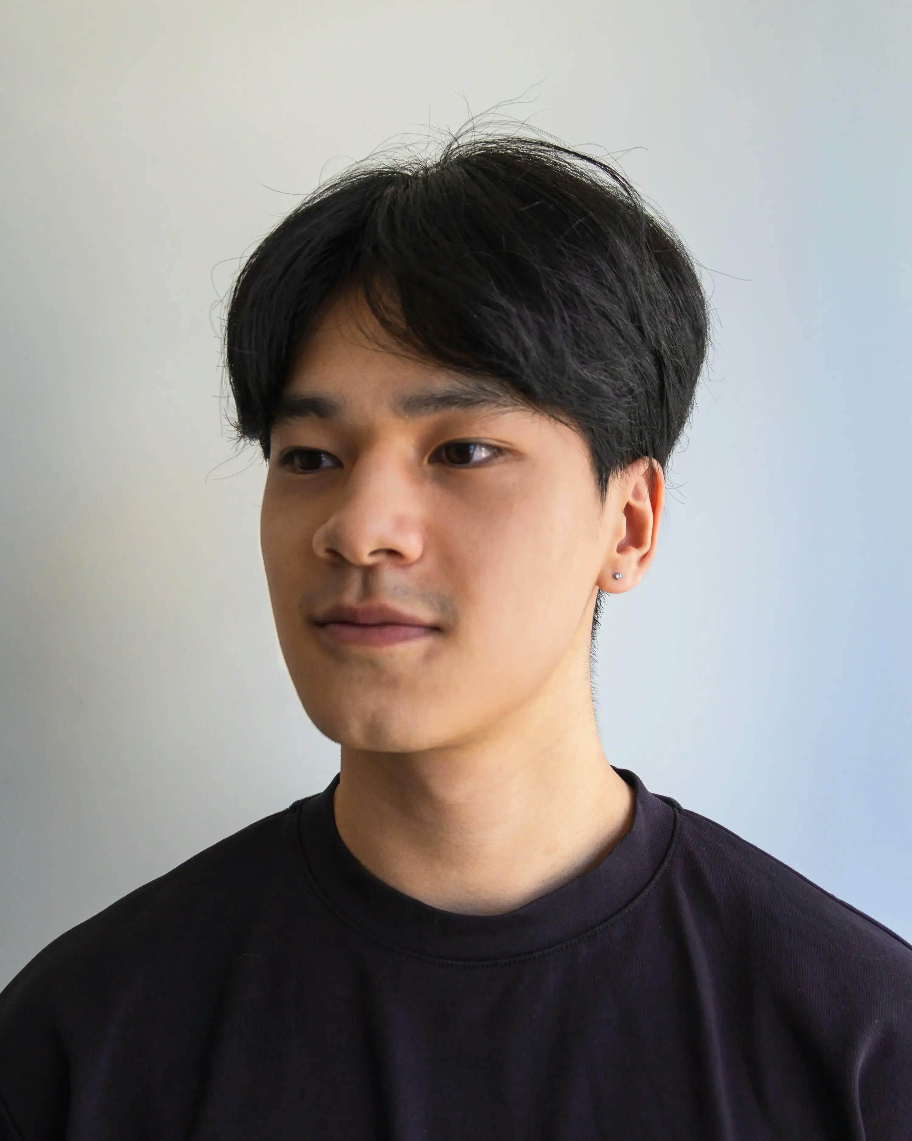 Headshot of Huy wearing a black tshirt against a white background